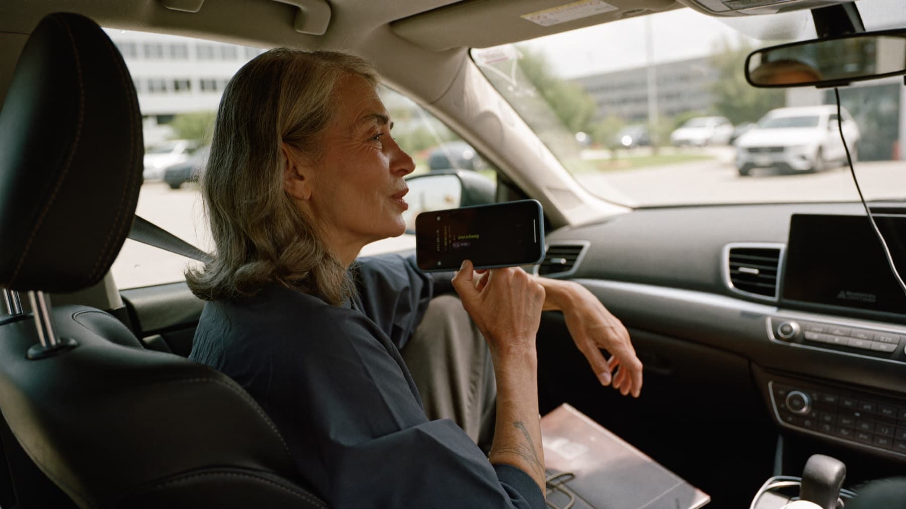A saleswoman in her fifties sits in her parked car right after a meeting, speaking a voice memo into her phone. Illustration.