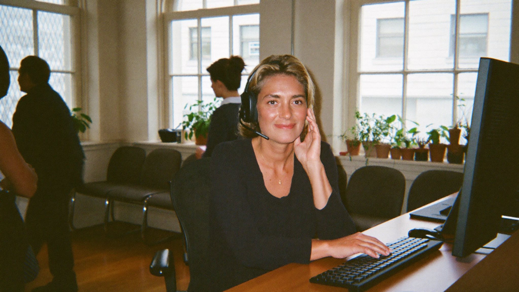 A receptionist on a headset in a bright office, taking the call