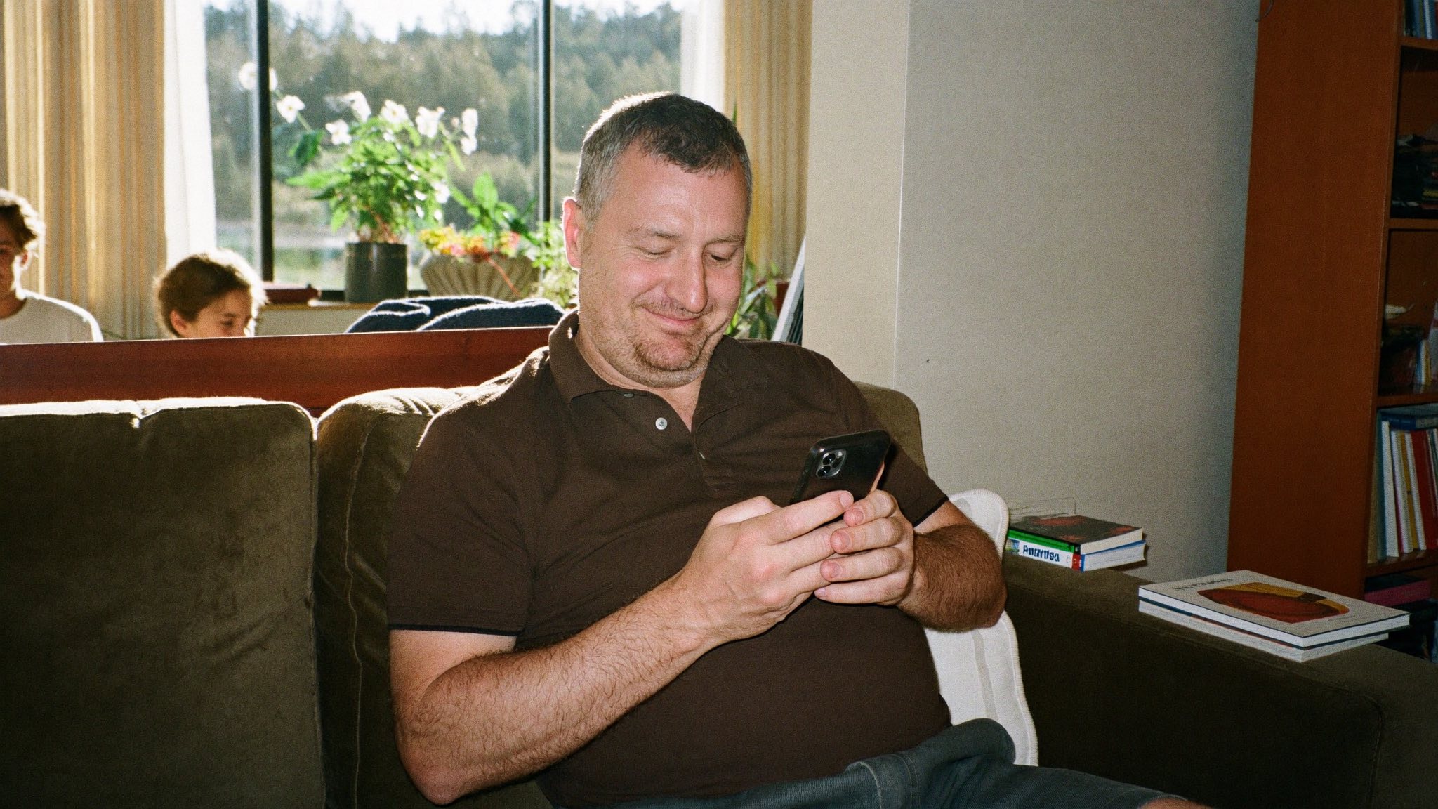 A man on his sofa in afternoon light, finding what he needed on his phone straight away