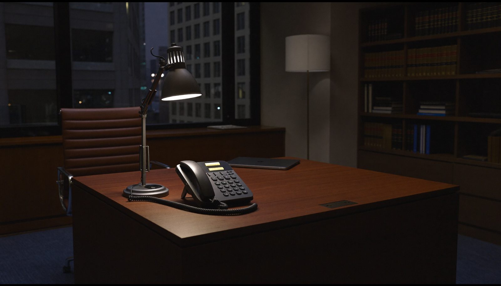An unanswered phone glowing on an empty law-office desk after hours